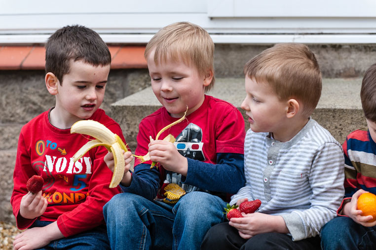 A group of children sit in a school playground eating their playtime snack